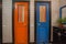 Wooden doors of old house bathroom. Blue and red door and mirror over washbasin