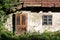 Wooden doors and windows mounted with decorative rusted metal hinges on dilapidated wall of small abandoned family house with