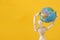wooden dummy figure holding globe over yellow background