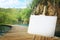 Wooden easel with blank canvas bridge over river and beautiful waterfall. Space for text