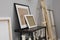 Wooden easel near shelving unit with canvases and small sculptures in artist\\\'s studio
