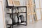 Wooden easel near shelving unit with canvases, vases and small sculptures in artist\\\'s studio