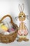Wooden easter bunny with a wicker basket filled with knitted easter eggs