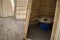 Wooden ecological composting toilet on countryside with sawdust