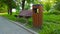 Wooden empty bench for rest and trash container in city park. Concept of cleanliness, ecology and comfortable urban environment.