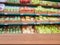 Wooden empty table in front of blurred supermarket fruits and vegetables shelf