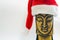 Wooden face of buddha in santa claus hat on white background, selective focus, copy space