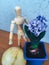 wooden faceless man gives blue flowers