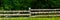 Wooden fence against the background of deciduous forest in the evening, rural landscape. Web banner