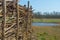Wooden fence of braided branches in a field in wetland in a blue sky in springtime