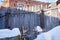 wooden fence and a broken machine, covered in snow. Abandoned territory of an old factory