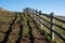 Wooden fence at cliff edge, with shadow on the grass, photographed at Hope Gap, Seaford, East Sussex UK