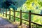 Wooden fence, countryside road. Green trees in park with pathway.