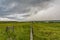 A wooden fence dividing the photograph in half stretches towards the horizon