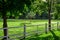 Wooden fence enclosing an animal pasture with green grass.