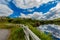 Wooden fence next to a path in the Clifden bay with clouds reflecting in the water and the village in the background