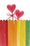 Wooden fence in rainbow colors and two lollipops in heart shape