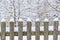 Wooden fence in snow with trees
