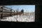 A wooden fence stretches out across barren snowy farmland littered with dead stalks