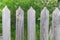 Wooden fence with triangular tops in the village in the afternoon under the sun with a green background