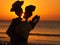 Wooden figure of a dancing couple against the background of sunset.