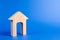 Wooden figure of a house with a large doorway on blue background. concept of buying and selling real estate, rent, investment.