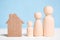 Wooden figures family with cardboard house on blue background