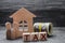 Wooden figures of the family stand near a wooden house and money. Property tax. Payment of taxes to the state. Law-abiding citizen