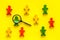 Wooden figures of people under black magnifying glass on yellow background. Recruitment, hiring, leadership concept.
