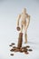 Wooden figurine standing and making stack of coins