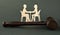 Wooden figurines of a man and a woman sitting at a table against the background of a judge`s hammer