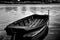 Wooden fishing paddle boat closeup anchored on the shore. monochrome finish