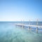 Wooden footbridge or catwalk and banister on ocean water. Long e