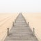 Wooden footbridge on a foggy beach background.