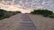 Wooden footpath through the sand leading to the beach. Beautiful morning sky with fluffy clouds