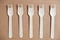 Wooden forks on a cardboard background. Eco friendly disposable tableware. Top view. Copy, empty space for text