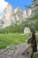 A wooden fountain with carvings along Vallunga Valley above Selva with Saint Silvestro Chapel and Mount Stevia in the background,