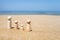 Wooden four figures of people on the sand of beach with sea view. Concept of happy family with two kids on holiday.