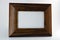 Wooden frame made of natural wood for photos and images covered with reflective varnish and located on a white plastic background.