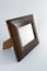 Wooden frame made of natural wood for photos and images covered with reflective varnish and located on a white plastic background.