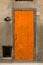 Wooden front door and house number 31 on old wall. Orange door on gray background