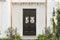 Wooden front door of white brick home with plants