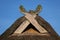 Wooden gabled boards in the form of horse heads on a thatched roof against a blue sky, typical of traditional houses in northern