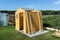 A wooden garden shed under construction standing on a concrete foundation in the garden, visible greenhouse.