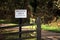 Wooden gate on a road through forest or woodland, with a sign sa