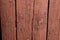 Wooden gates made of old painted red boards with a brown tinge and peeling texture