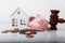 Wooden gavel, broken piggy bank and house model with coins close-up. Auction and bankruptcy concept