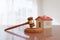 Wooden gavel and and house toy on wooden desk. Concept of real estate law. 3d illustration