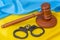 The wooden gavel of the judge against the background of the flag of Ukraine and handcuffs, the concept: the claim and indemnity, t