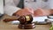 Wooden gavel of judge on table close-up, and blurred doctor doing paperwork in medical clinic.